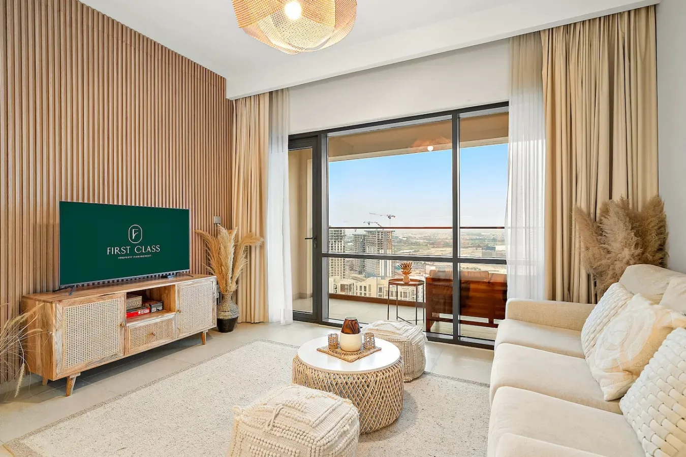 Una sala luminosa con asientos, televisión y puertas de vidrio que dan a un balcón.
