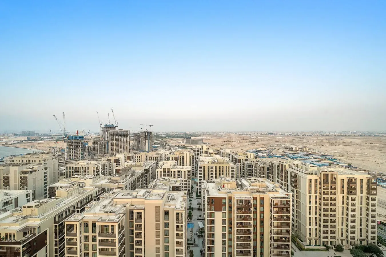 Una amplia vista urbana de edificios de apartamentos modernos, con grúas de construcción a lo lejos.
