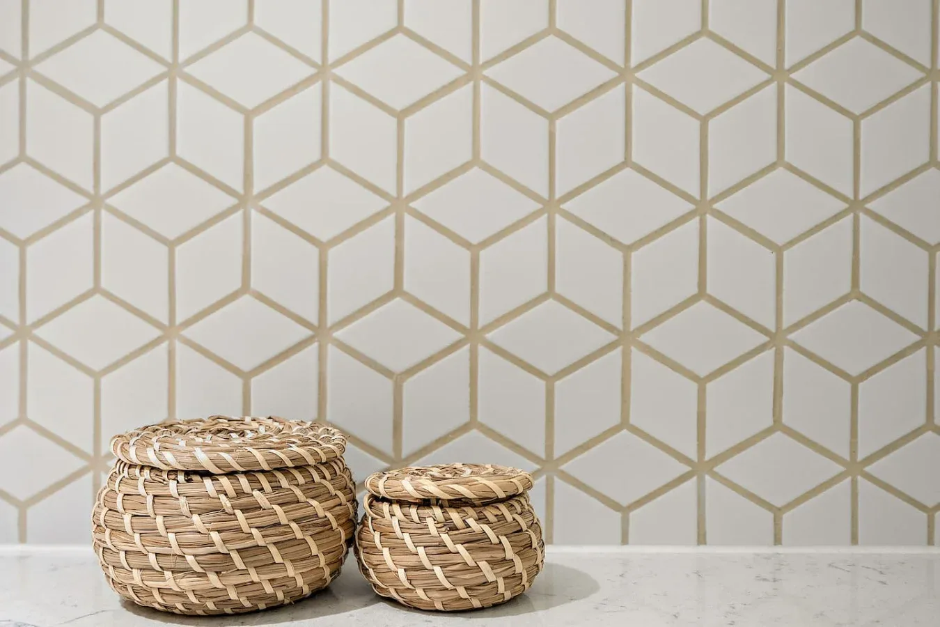 Cestas decorativas están frente a una pared con un patrón geométrico.