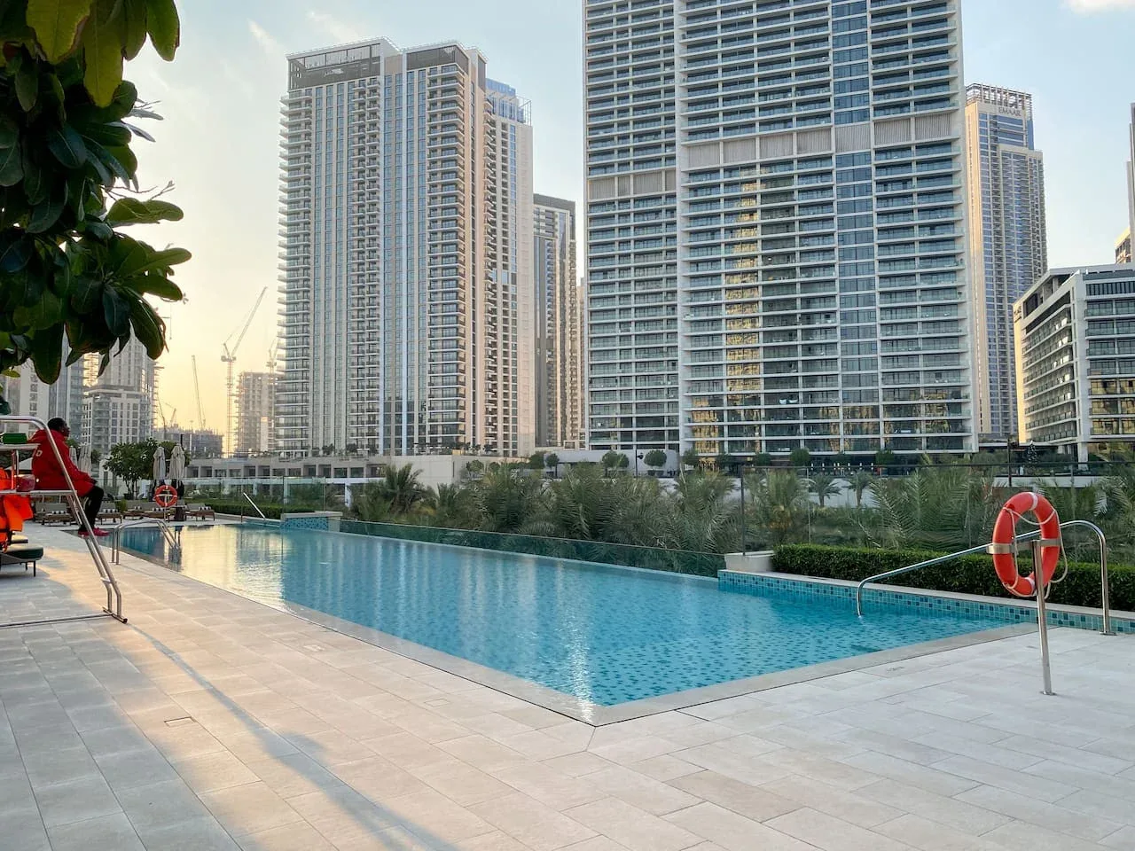 Una piscina al aire libre está junto a modernos edificios altos.