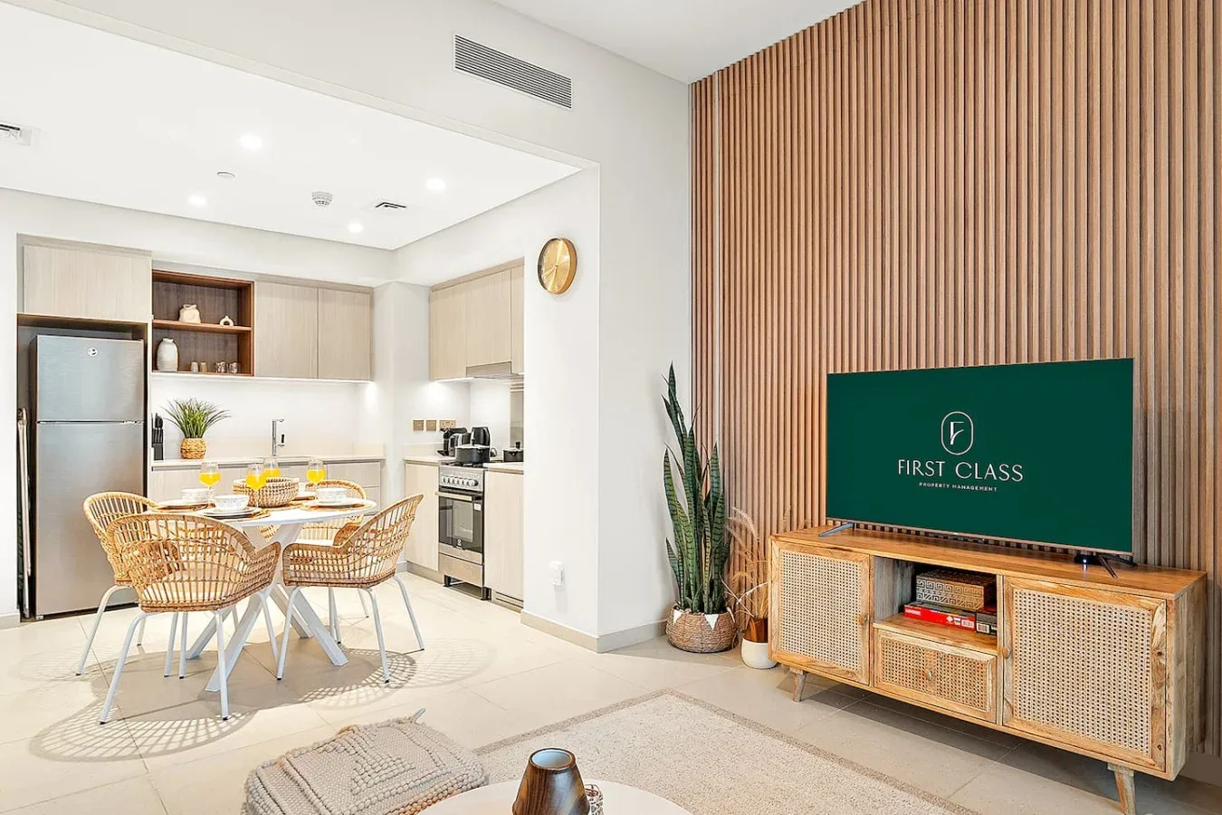 Una luminosa cocina-comedor abierta con un televisor frente a una pared de listones de madera.