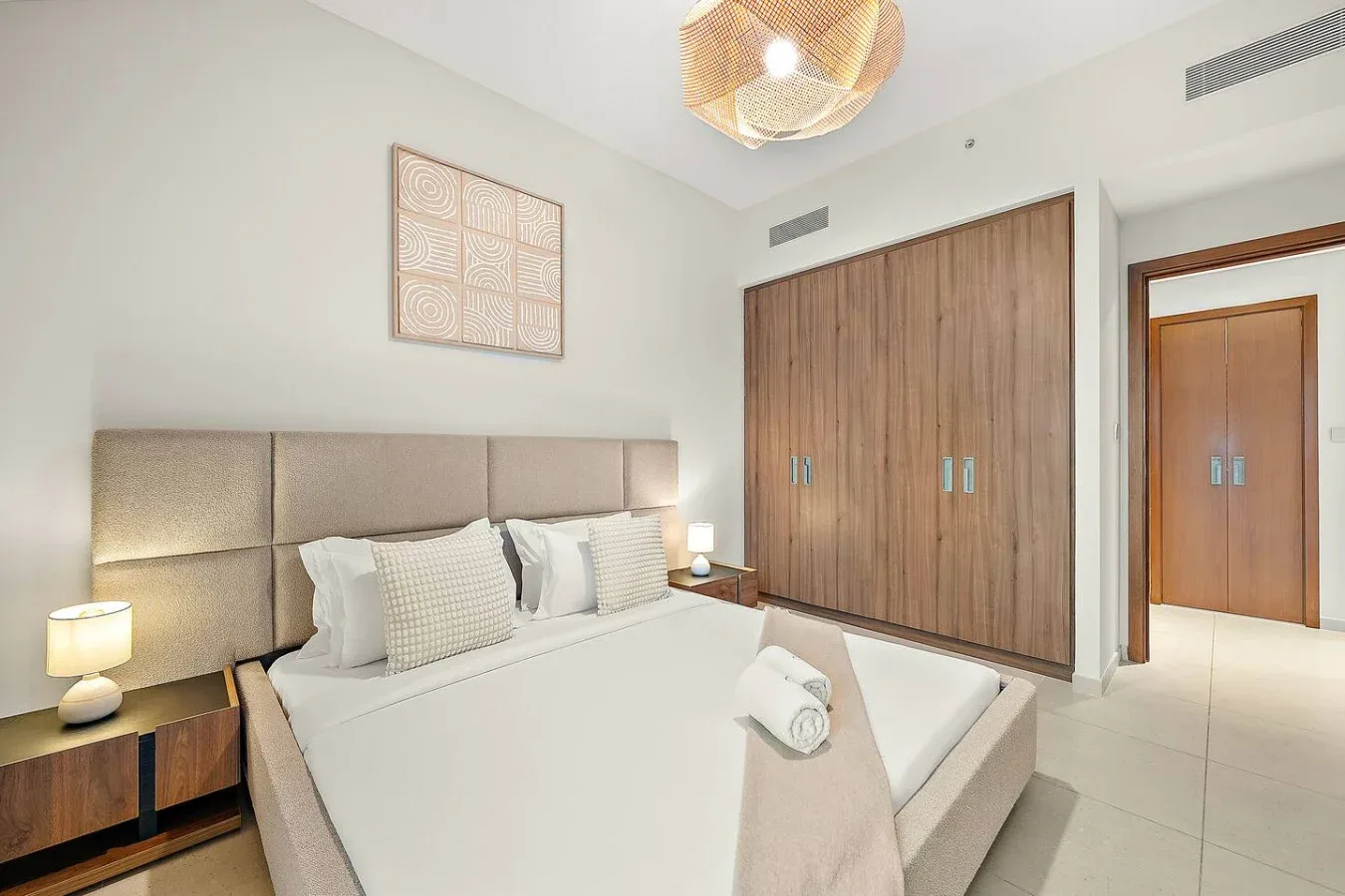 Un dormitorio con una cama bien tendida y amplias puertas de armario de madera.