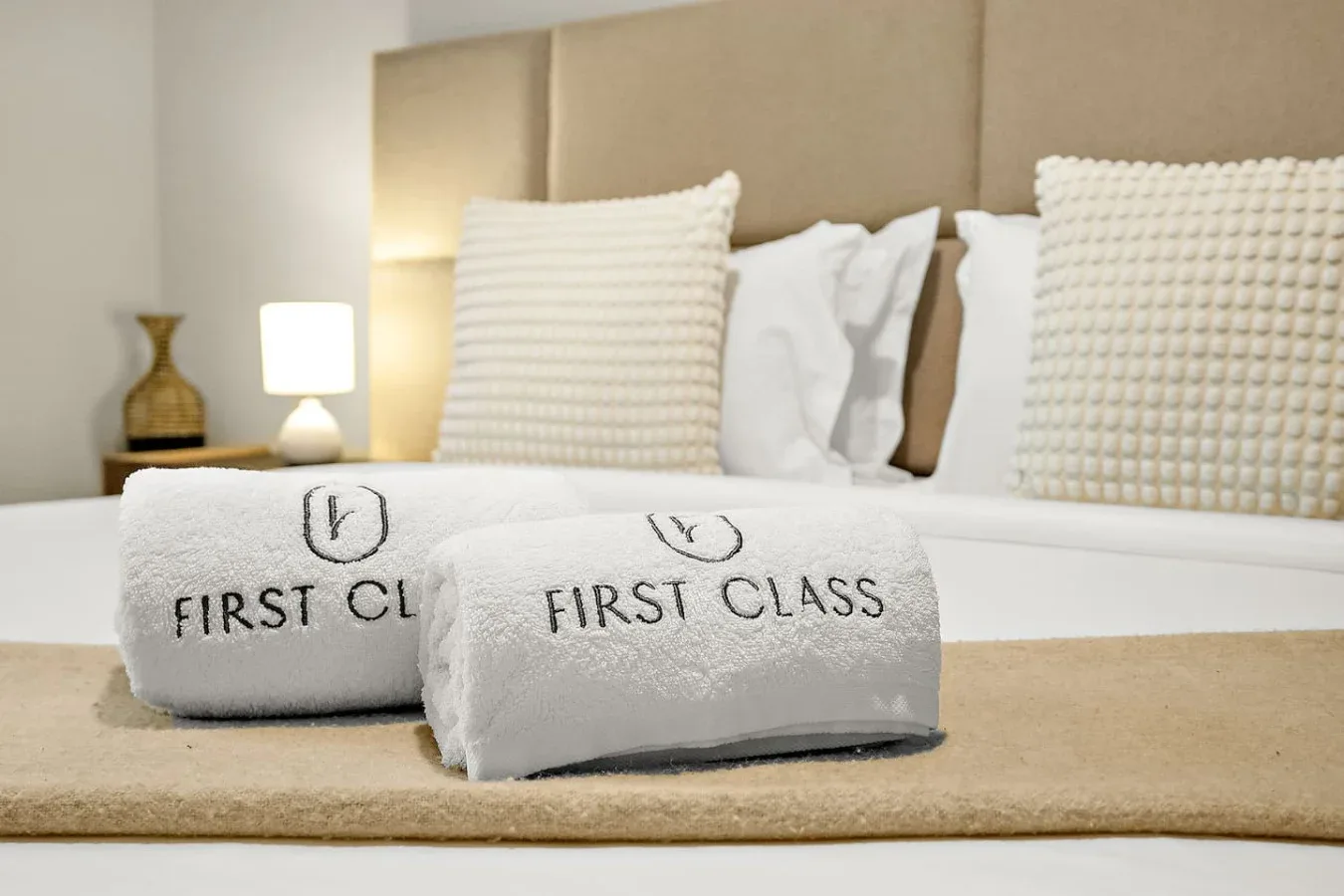 Una cama bien tendida con almohadas blancas y toallas dobladas en primer plano.