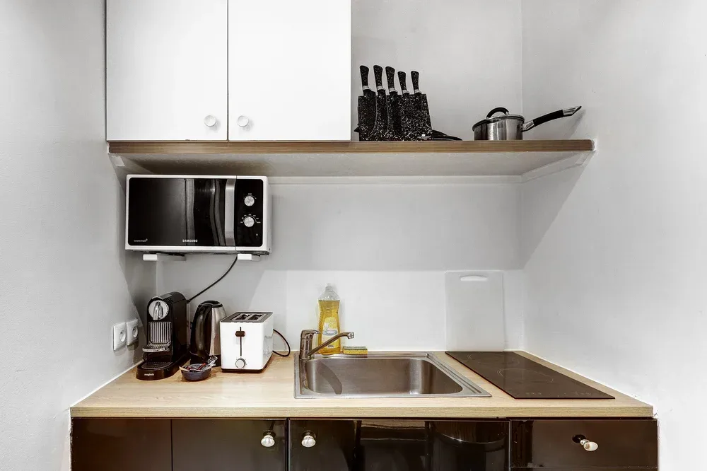 Una cocina compacta con fregadero, encimera y pequeños electrodomésticos.