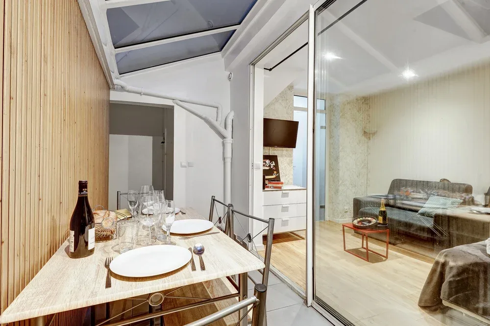 A dining area with a set table beside a glass partition and living space.