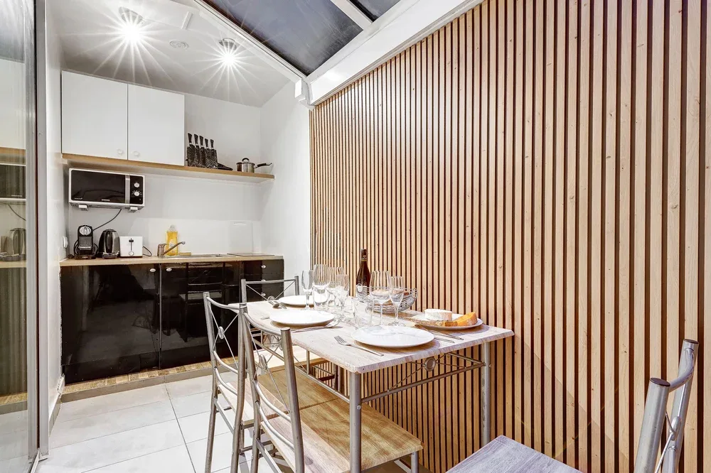 A dining area with a set table beside a compact kitchen.