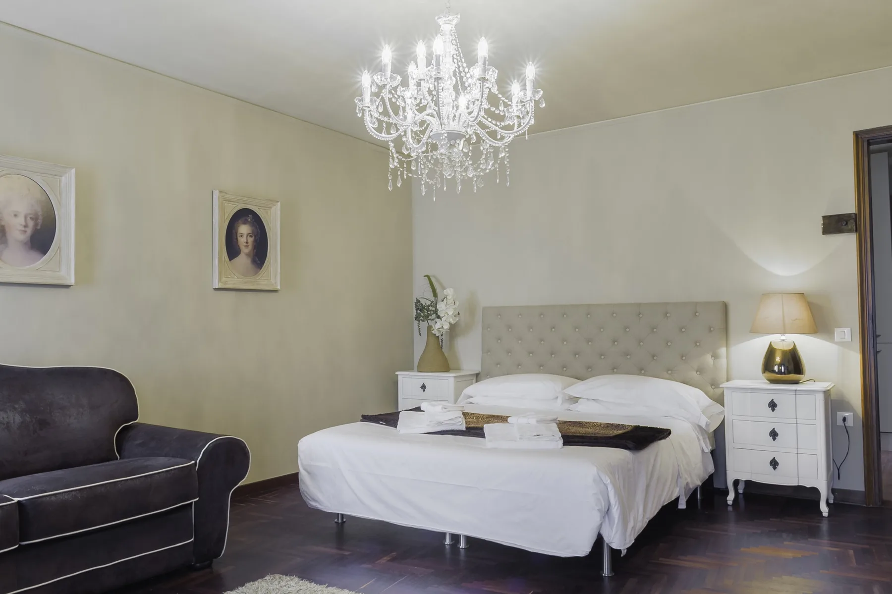 A bedroom with a white bed, bedside tables, and a crystal chandelier.