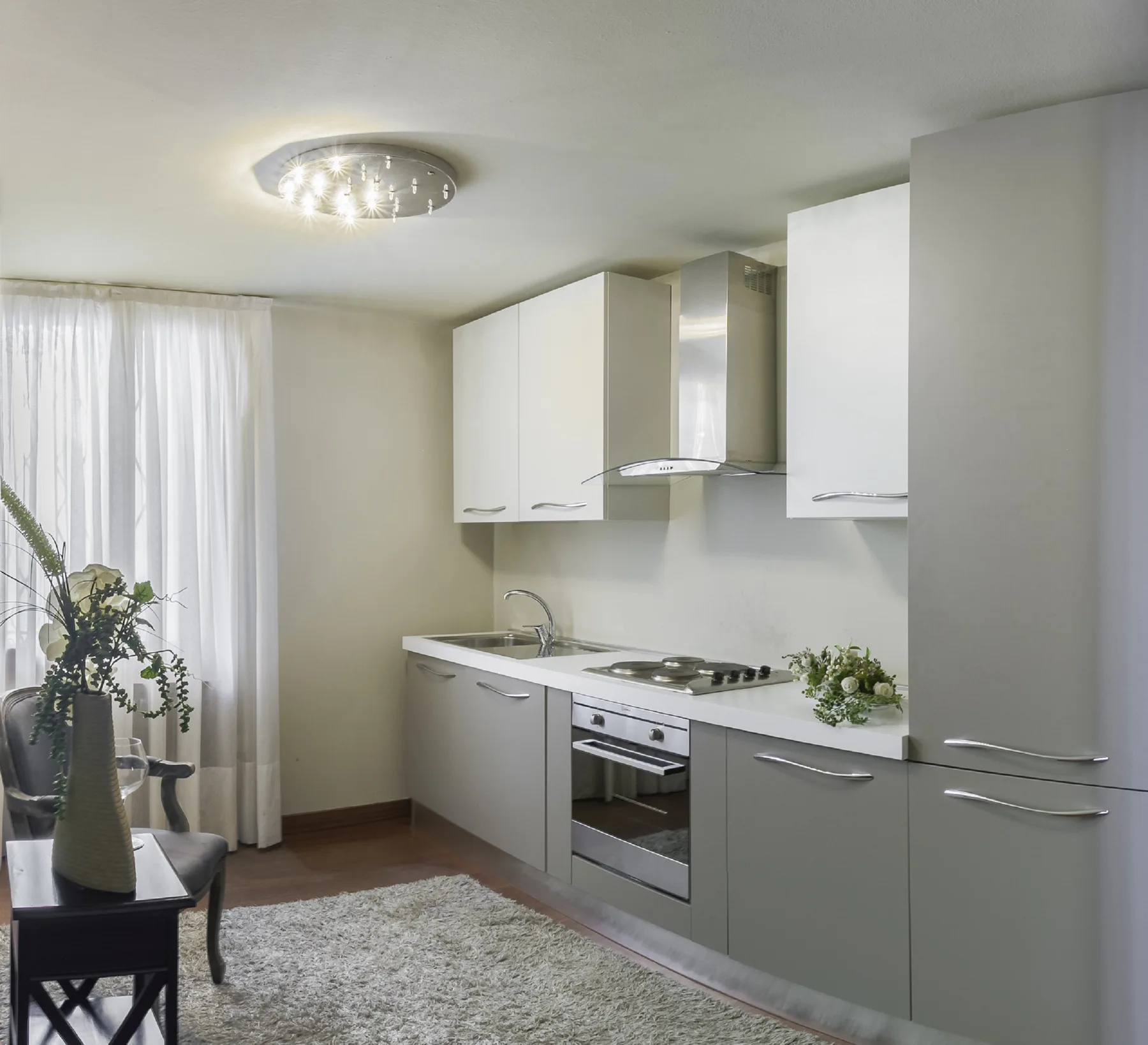 A modern kitchen with white cabinetry, a cooktop, and an oven.
