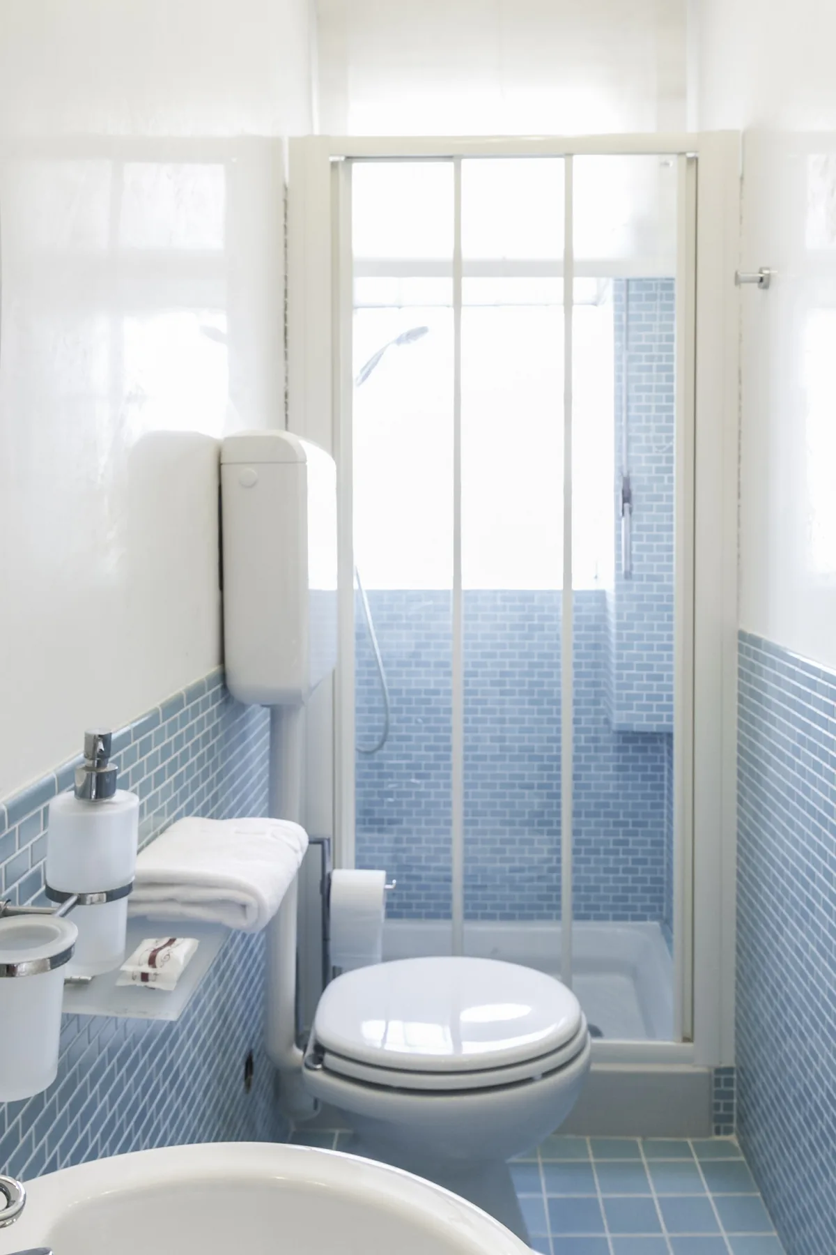 A tiled bathroom with a toilet, sink, and glass shower enclosure.
