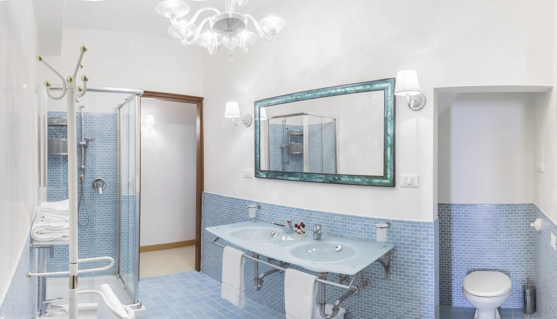 A bright bathroom with a glass shower and a wide sink beneath a mirror.