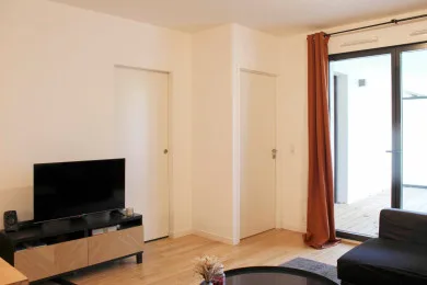 A living room with a television, seating, and a bright window.