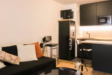 A compact living area with seating beside a small kitchen.