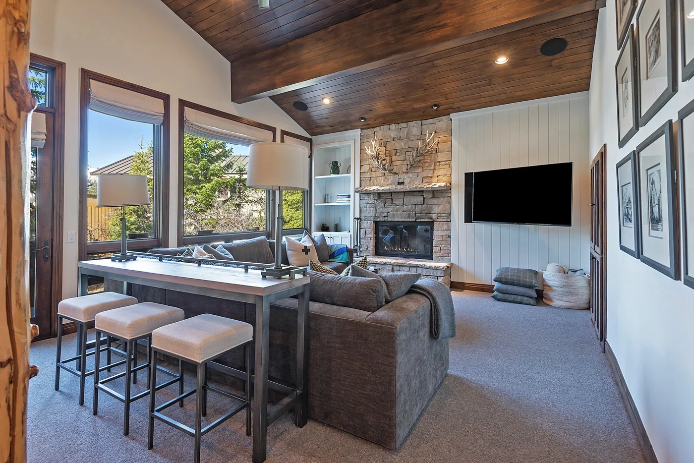 A living room with seating, a stone fireplace, and a television.