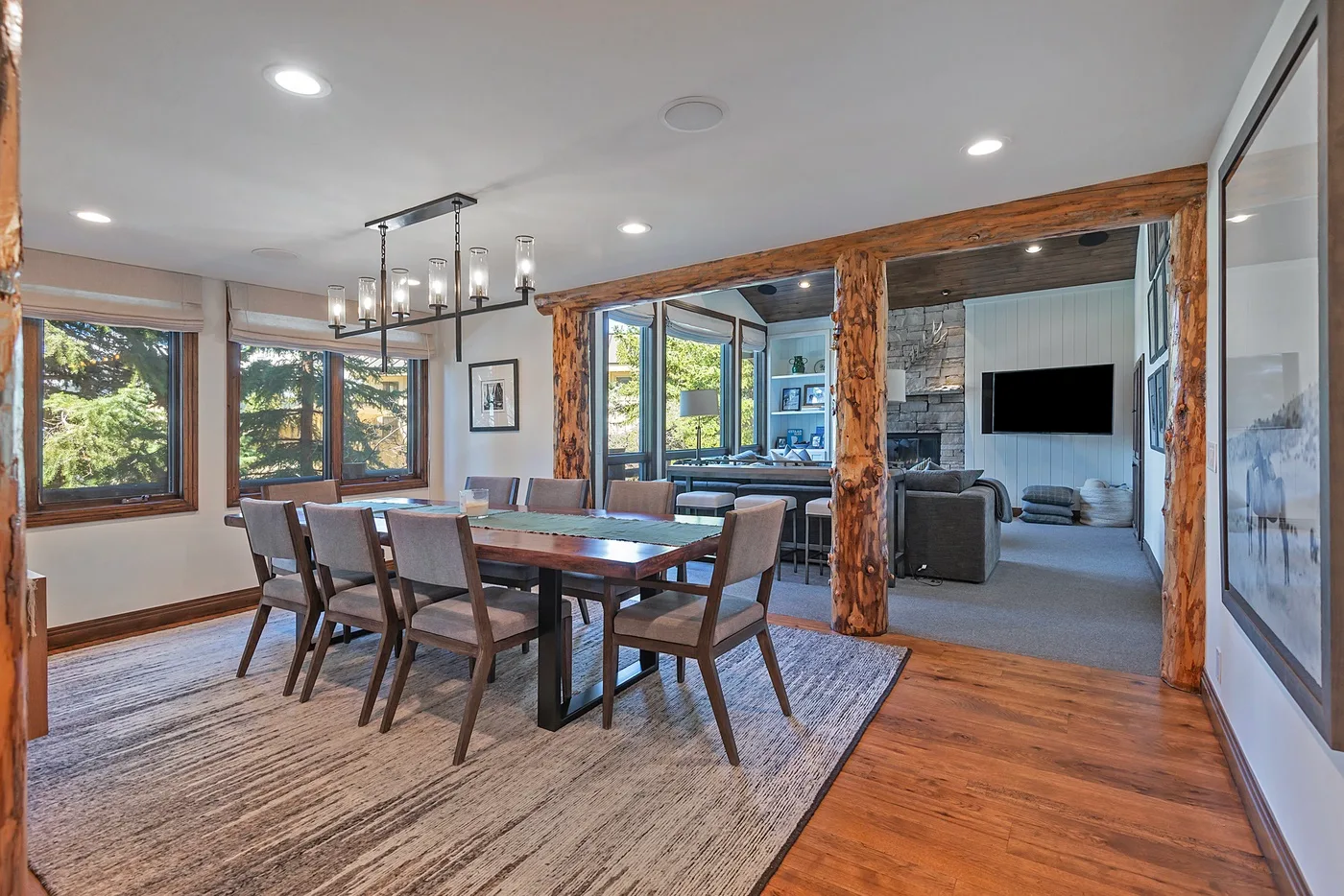 A dining area with a long table and seating beside a living room.