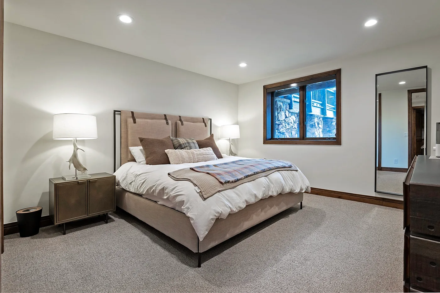 A bedroom with a large bed, bedside tables, and a window.