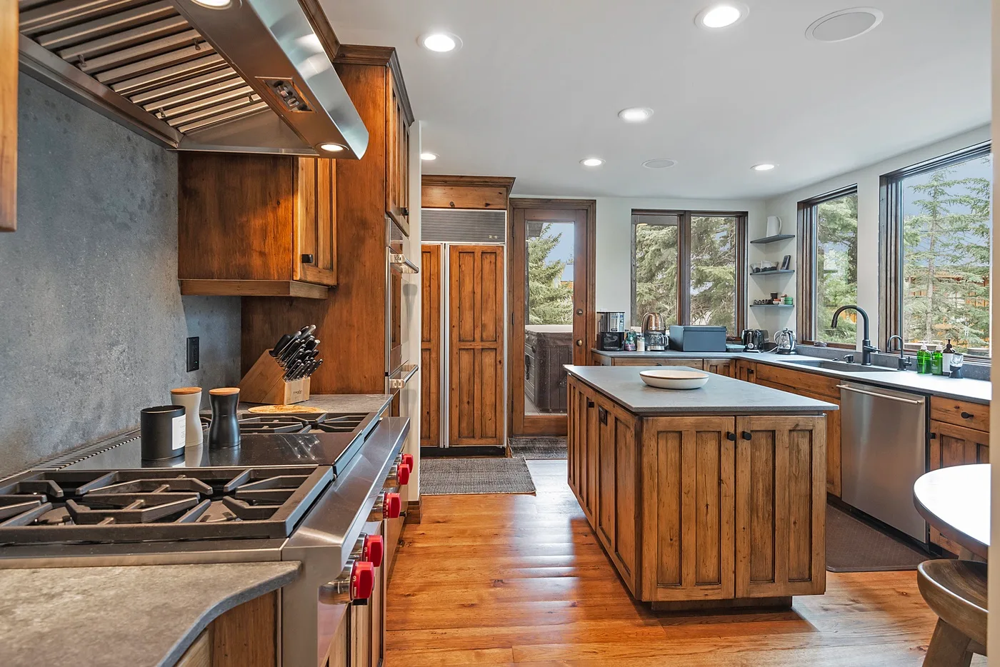 A spacious kitchen with a wood-fronted island and large windows.