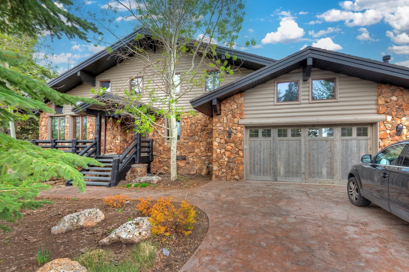 A stone-and-wood house exterior with a driveway and attached garage.
