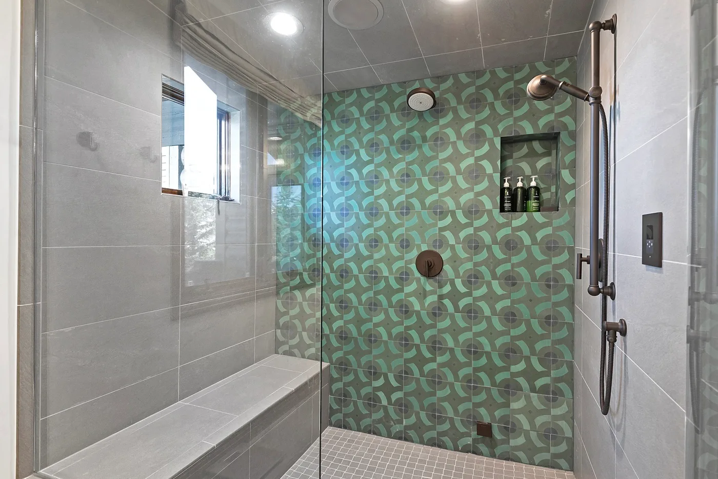 A tiled shower area features patterned green walls and a built-in bench.