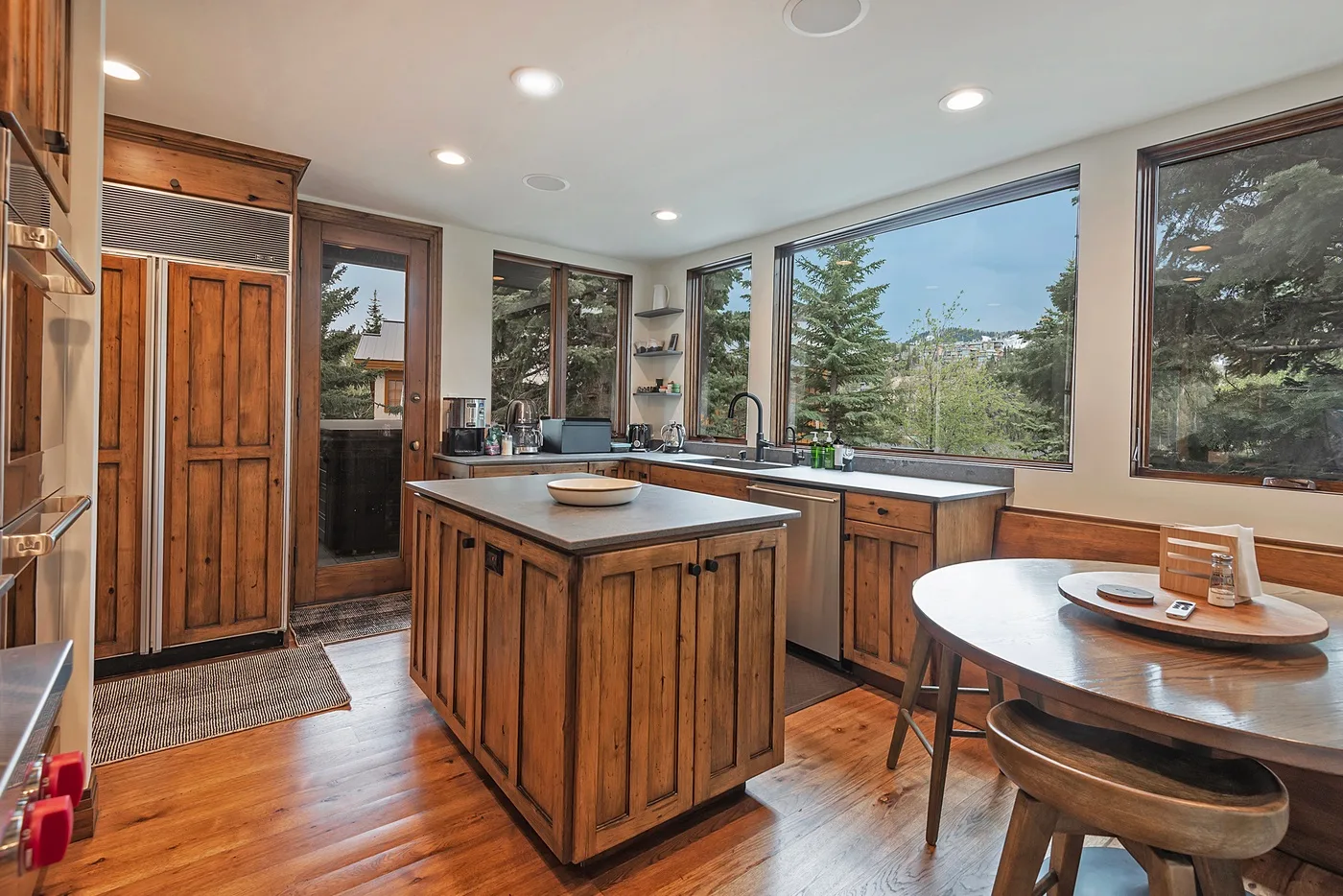 A bright kitchen with a central island and large windows overlooking trees.