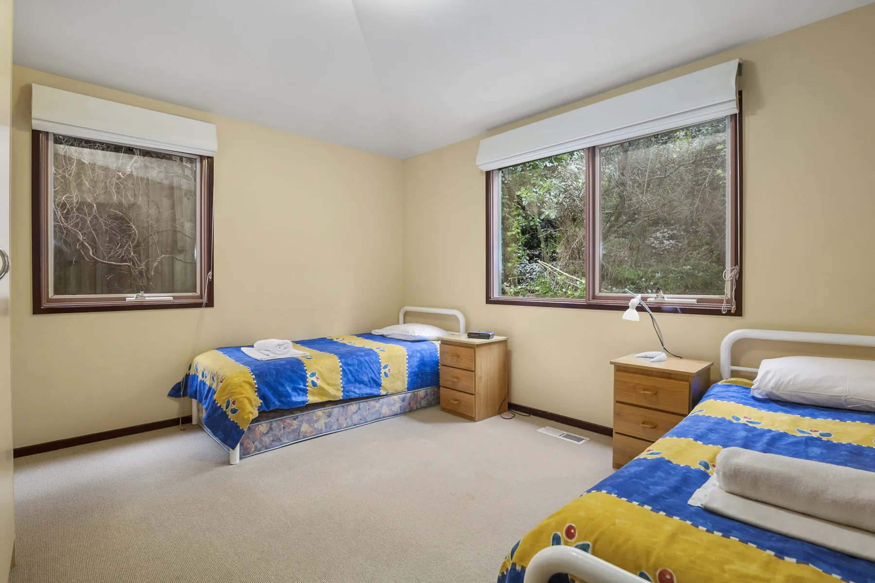 Un dormitorio con dos camas individuales y ropa de cama azul y amarilla.