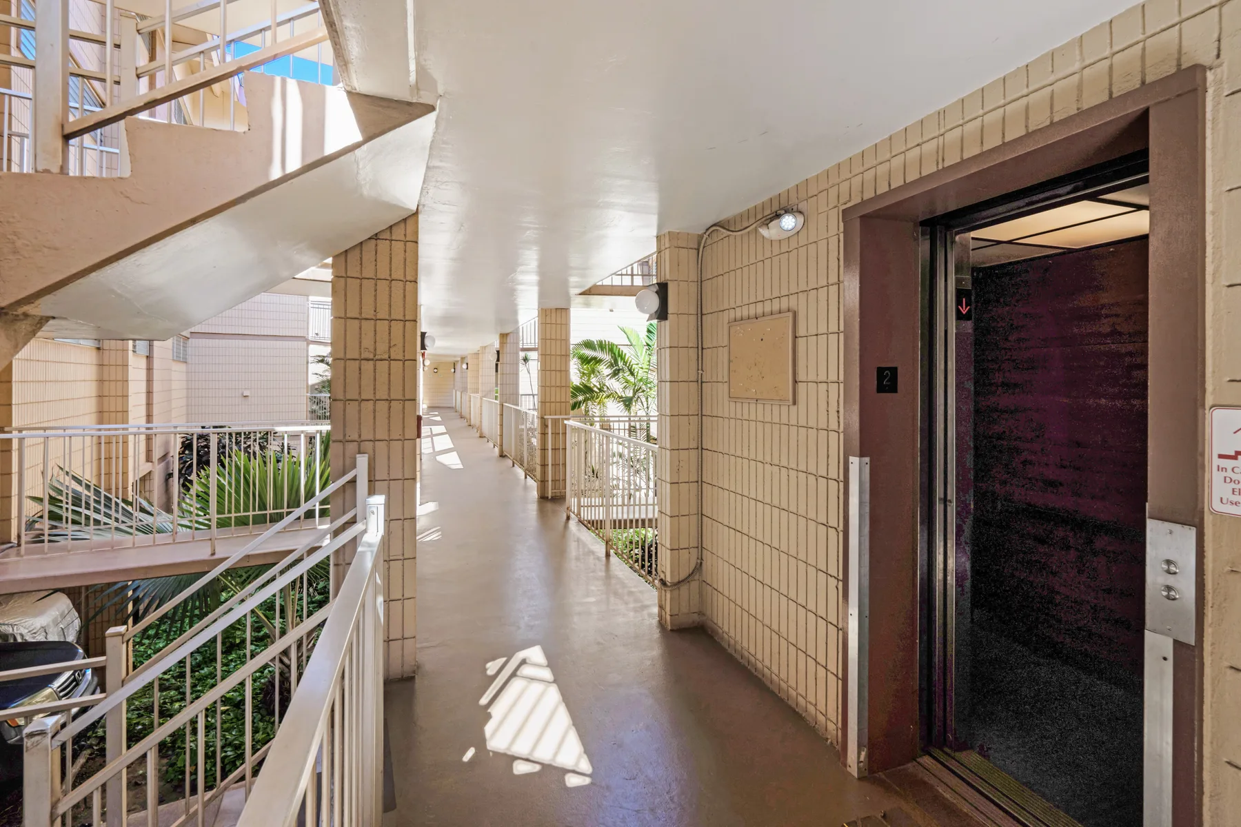 A tiled corridor with metal railings and an open elevator.