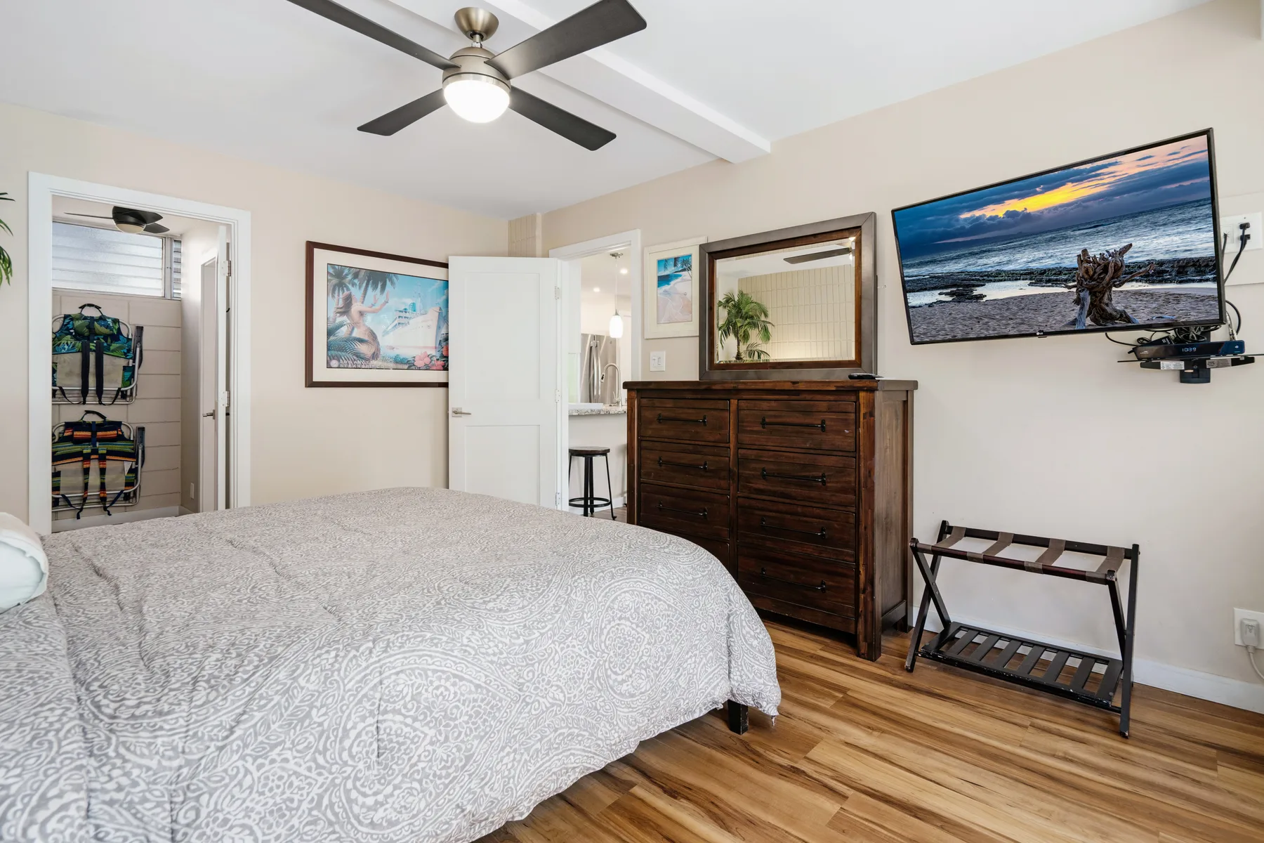A bedroom with a bed, dresser, and wall-mounted television.
