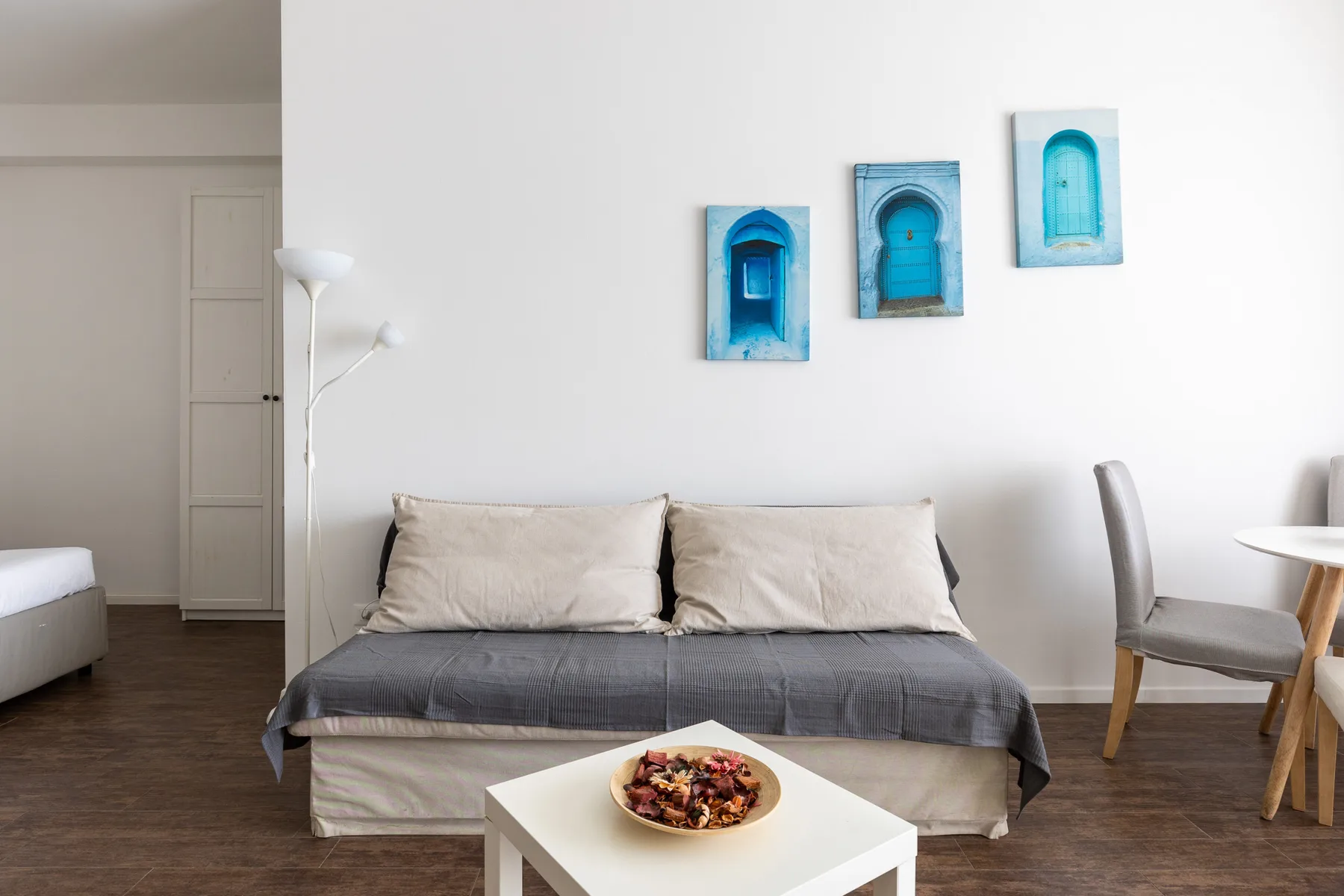 Un dormitorio con una cama, tres adornos azules en la pared y una mesa pequeña.