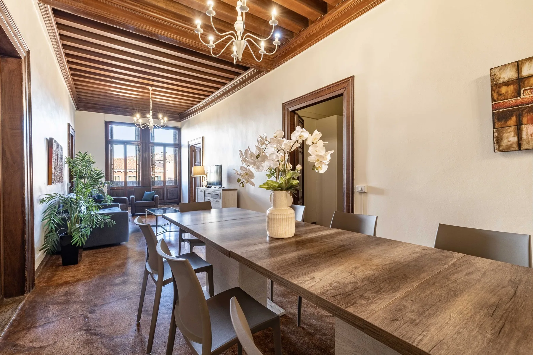 Comedor con una mesa larga de madera y sillas bajo un techo con vigas.