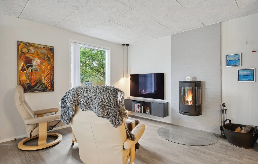 Una sala luminosa con asientos, un televisor y una chimenea encendida.