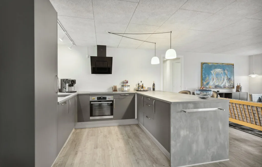 Una cocina moderna con gabinetes grises, una isla y lámparas colgantes.