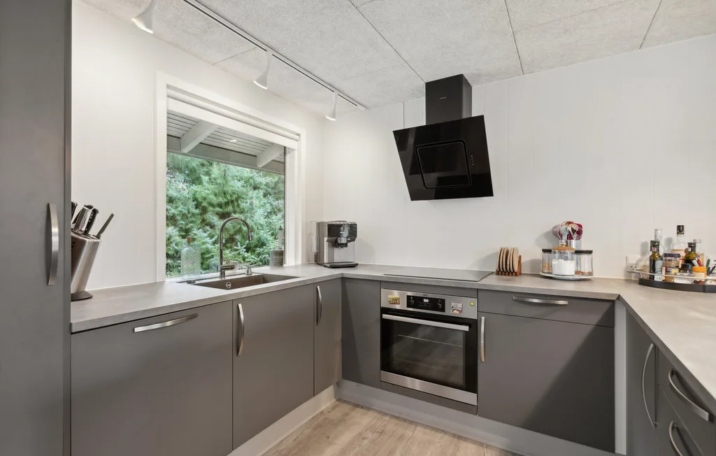 Una cocina moderna con gabinetes grises, fregadero y horno.
