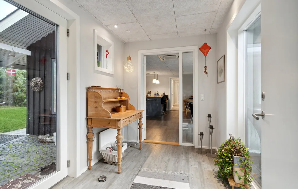 A bright entryway with a wooden console table and glass doors opening to a garden.