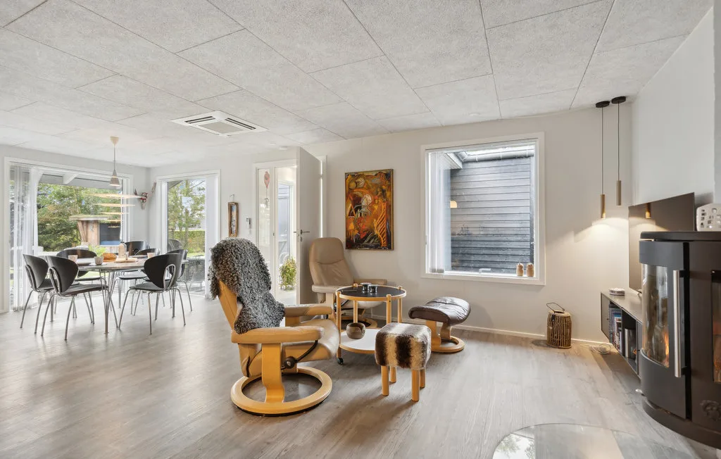 Una sala luminosa con asientos, un comedor y ventanas grandes.