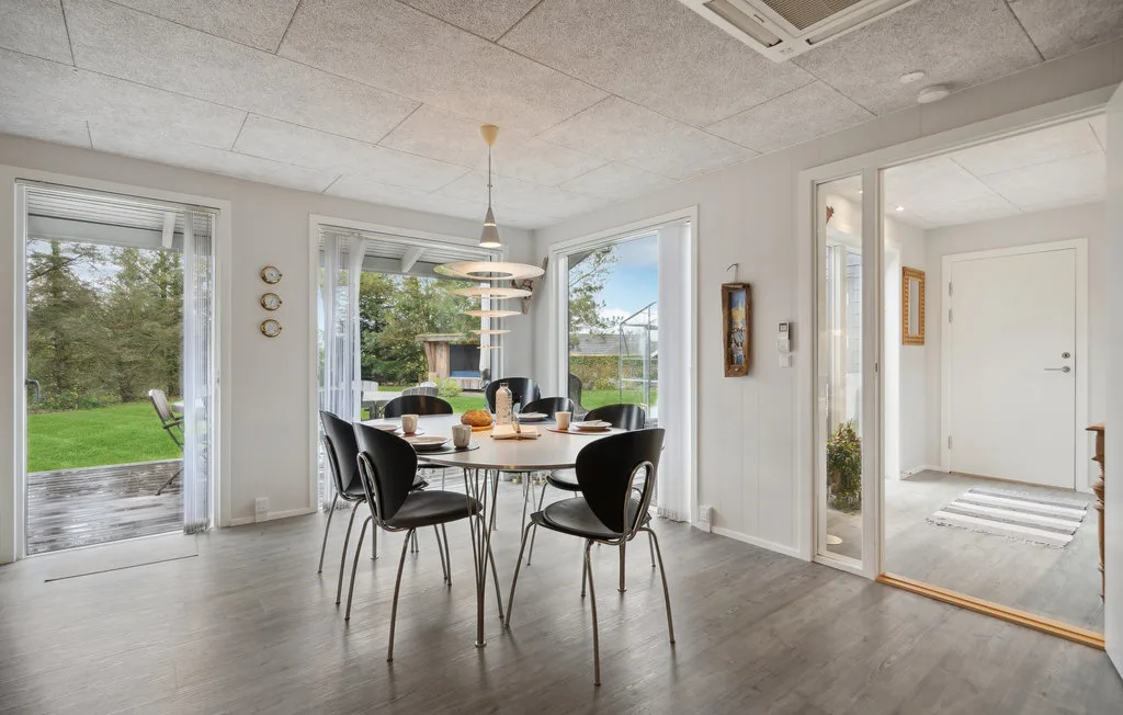A bright dining area with a round table and chairs beside large windows.