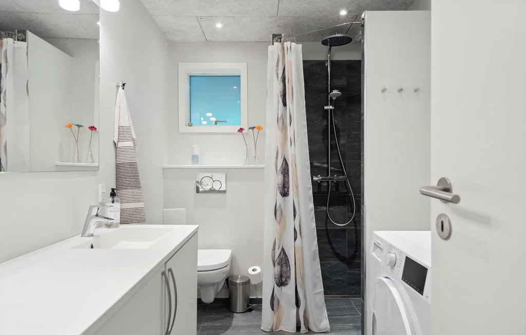 Un baño luminoso con lavabo, inodoro y ducha con cortina.
