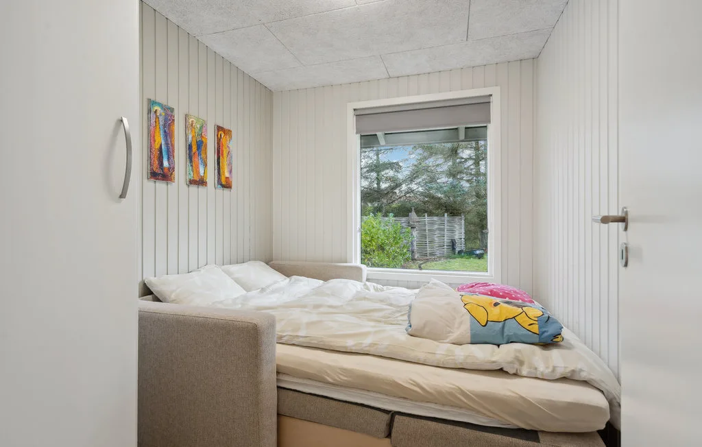 Un dormitorio con una cama y una ventana con vistas a la vegetación.