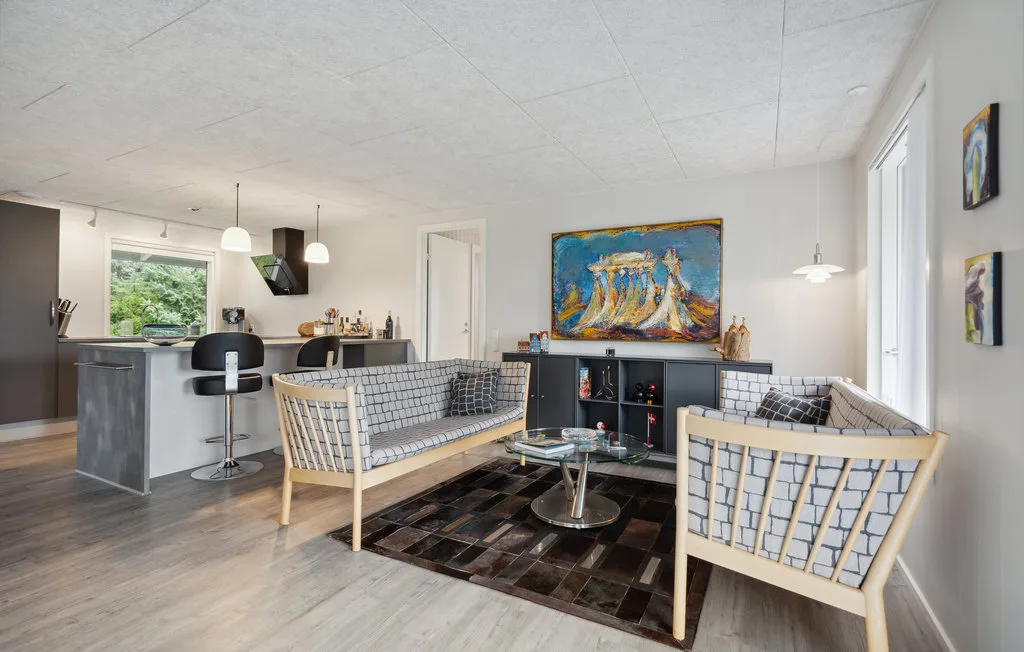 Una sala de estar diáfana con asientos, una mesa de centro y una barra de cocina.