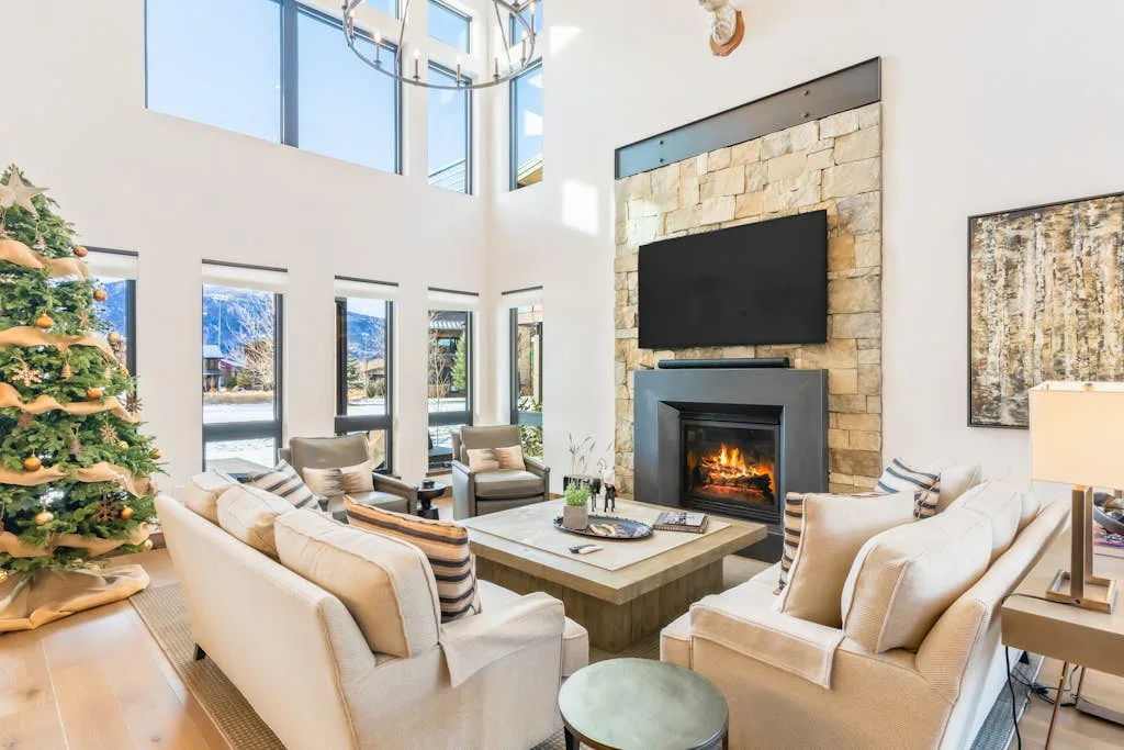 Una luminosa sala de estar con asientos alrededor de una chimenea y un televisor.