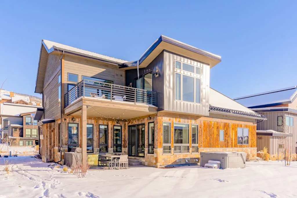 Una casa moderna de varios niveles se encuentra en un entorno exterior cubierto de nieve.