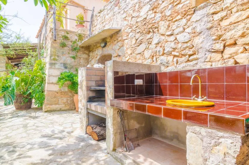 An outdoor kitchen with a tiled counter, sink, and built-in grill.