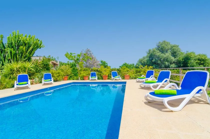 An outdoor swimming pool with blue lounge seating around the deck.