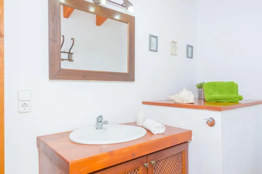 A bathroom vanity with a sink, mirror, and folded green towels.