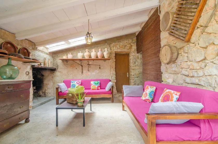 A rustic stone sitting room with bright pink seating and a low table.