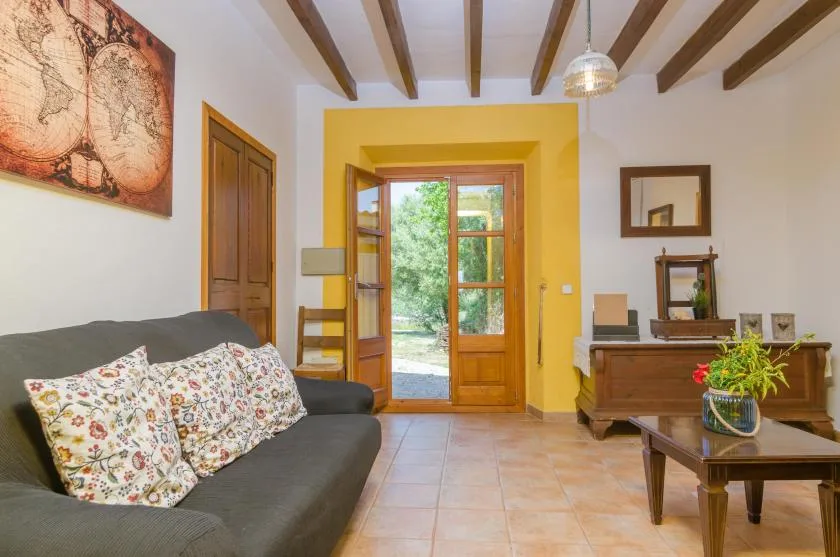 A living room with a sofa and a wooden doorway opening onto a garden.