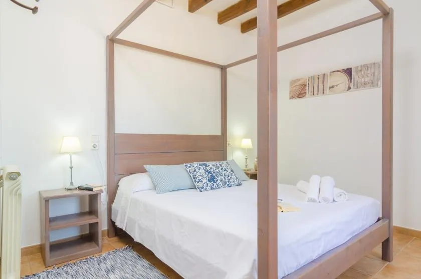 A bedroom with a white bed, bedside tables, and a canopy frame.