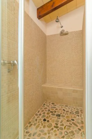 A tiled shower with a pebble-patterned floor and wall-mounted showerhead.