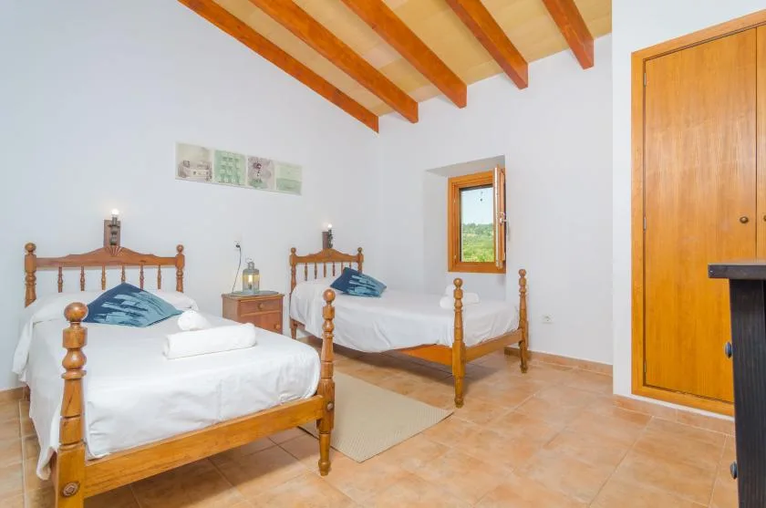 A bright bedroom with two wooden beds and a small window.