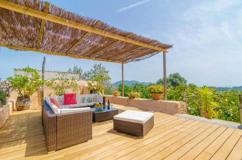 An outdoor terrace has cushioned seating beneath a woven shade canopy.