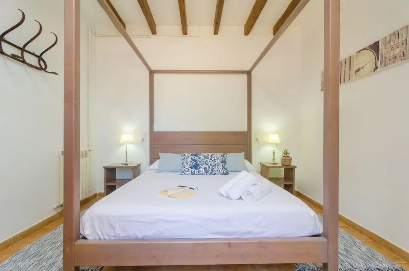 A bedroom with a large bed, bedside tables, and exposed ceiling beams.