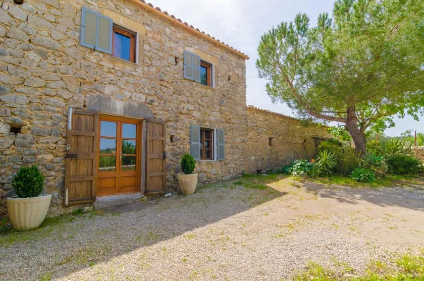 A stone house exterior with wooden shutters and a gravel courtyard.